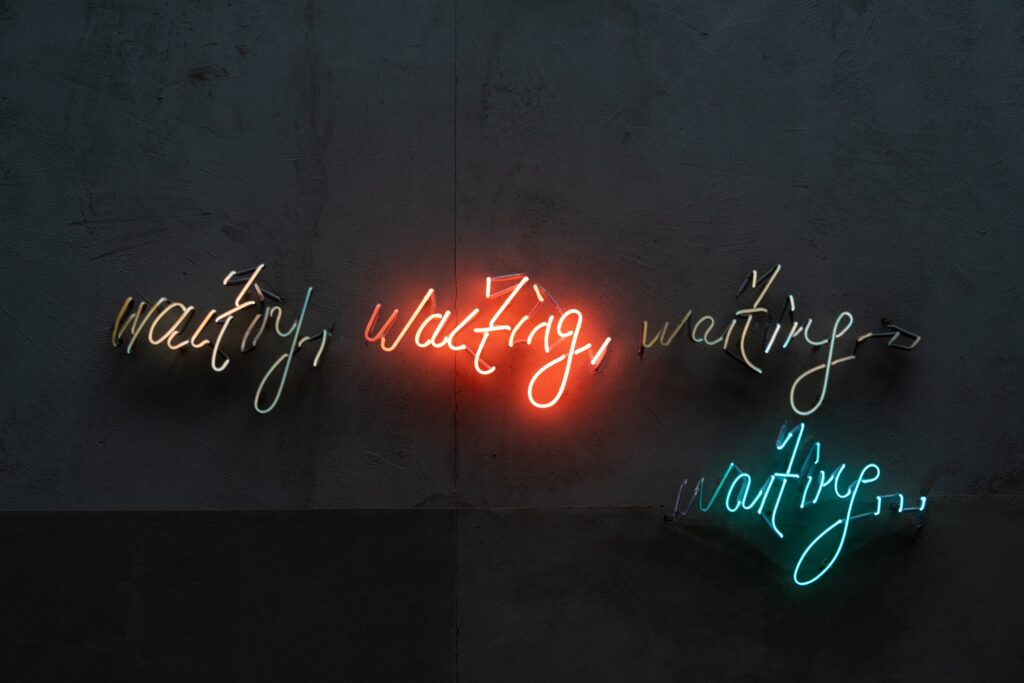 Multiple neon signs saying waiting
